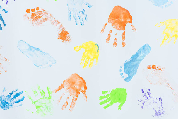 lasten käsien ja jalkojen värilliset jäljet valkoisella pohjalla
 - Valokuva, kuva