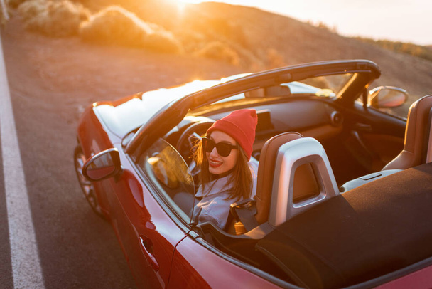 Femme voyageant en voiture sur une belle route pendant un coucher de soleil
 - Photo, image