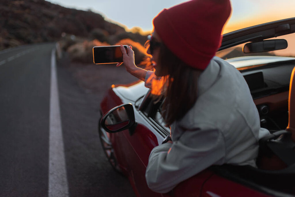 Nainen matkustaa autolla kauniilla tiellä auringonlaskun aikana
 - Valokuva, kuva