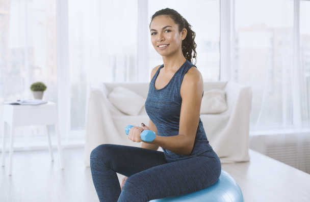 Encantadora señora latina haciendo ejercicio con pelota de fitness y pesas en casa, espacio para copiar
 - Foto, imagen
