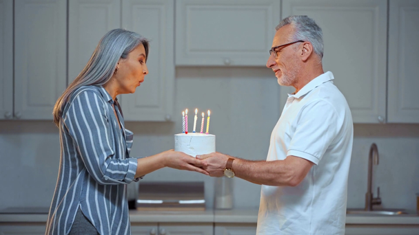 Senior Mann hält Geburtstagstorte in der Nähe von asiatischer Frau  - Filmmaterial, Video