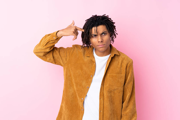 Young African American man with corduroy jacket over isolated pink background making the gesture of madness putting finger on the head - Фото, зображення