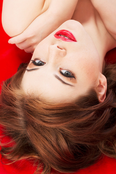 Attractive young naked woman lying on a red background. - Fotografie, Obrázek