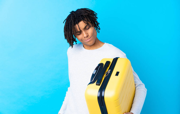 Young African American traveler man holding a suitcase with sad expression - Photo, Image