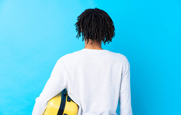 Jovem viajante afro-americano segurando uma mala na posição traseira
 - Foto, Imagem