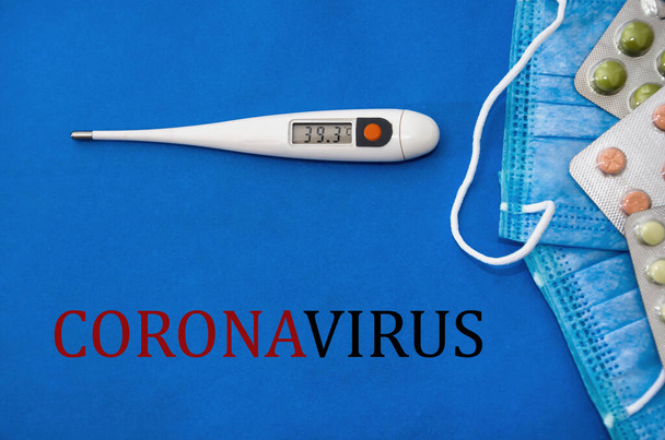 碑文「コロナウイルス」。コロナウイルス2019-ncovの概念。保護呼吸マスクと薬。新しい中国のコロナウイルスの発生。青の背景。温度計のディスプレイの高温. - 写真・画像
