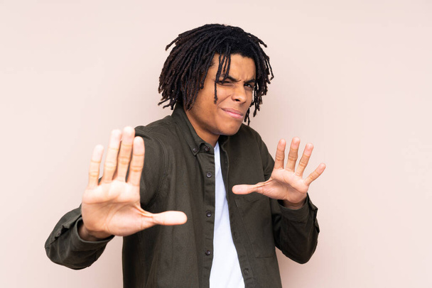 Νεαρός Αφροαμερικανός πάνω από απομονωμένο υπόβαθρο νευρικό τέντωμα χέρια προς τα εμπρός - Φωτογραφία, εικόνα