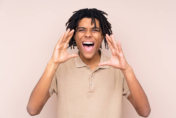 Молодой афроамериканец на изолированном фоне кричит с открытым ртом
 - Фото, изображение
