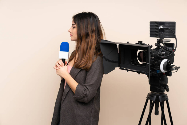 Mujer reportera sosteniendo un micrófono y reportando noticias sobre un fondo aislado mirando hacia un lado
 - Foto, imagen