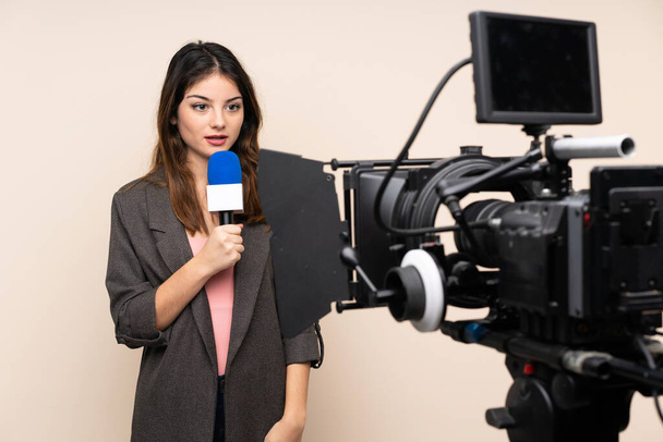 Reporter woman holding a microphone and reporting news over isolated white background - Photo, Image