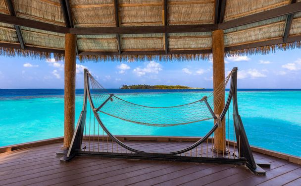 lege hangmat in een overwater terras op turquoise lagune - Foto, afbeelding