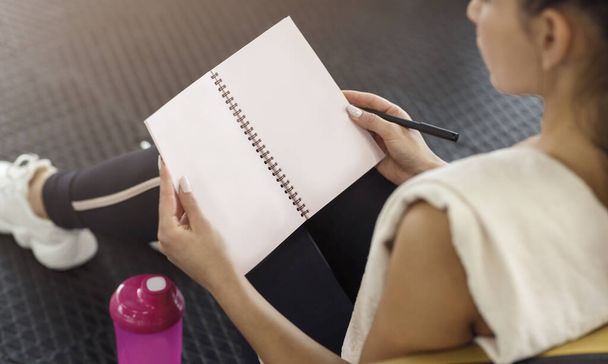 Unrecognizable woman writing her workout schedule in notebook, closeup - Фото, изображение
