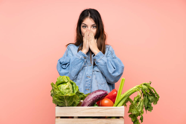 Jeune agricultrice tenant un panier plein de légumes frais avec expression faciale surprise - Photo, image