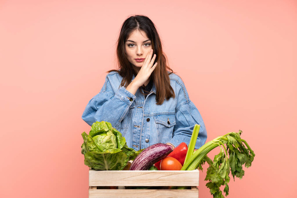 Mladá farmářka drží košík plný čerstvé zeleniny šeptající něco - Fotografie, Obrázek