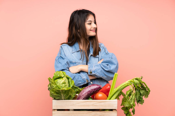 Jonge boer vrouw met een mand vol verse groenten kijken naar de zijkant - Foto, afbeelding