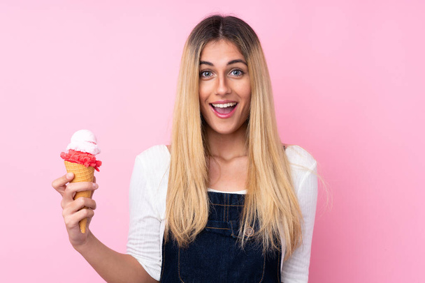 Young Uruguayan woman with a cornet ice cream over isolated pink background with surprise and shocked facial expression - Фото, изображение