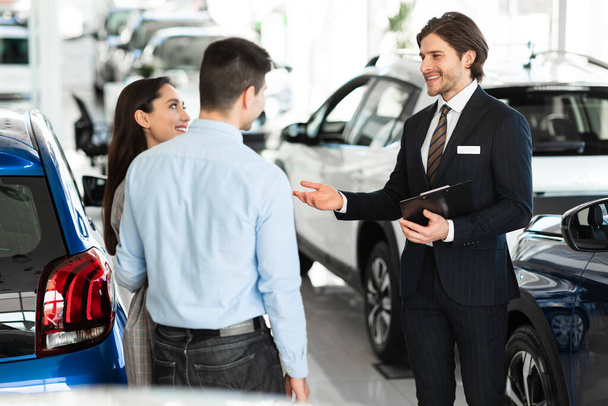 Salesman продаючи автомобіль клієнтам в дилерському шоурумі
 - Фото, зображення