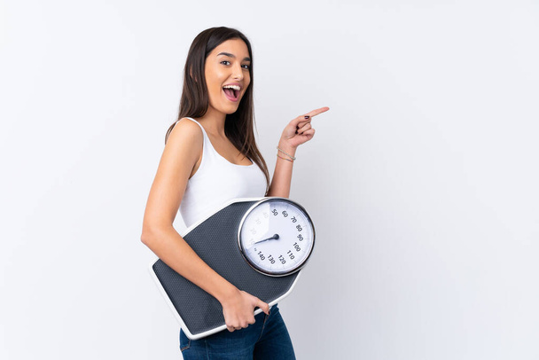 Young brunette woman over isolated white background with weighing machine - Фото, зображення