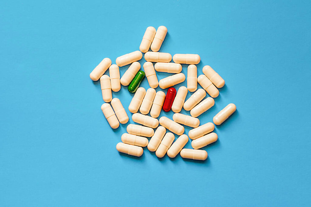 Weiße, grüne und rote Pillen auf blauem Hintergrund. - Foto, Bild