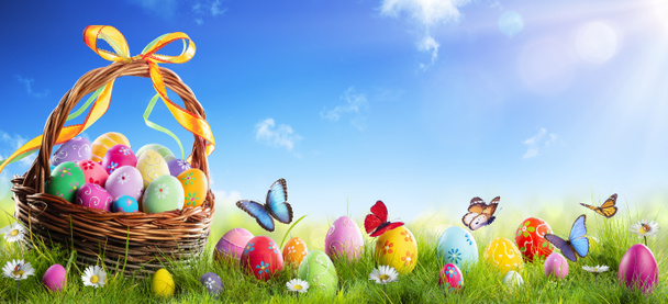 Huevos pintados de Pascua en la cesta en la hierba con fondo soleado de primavera
 - Foto, Imagen