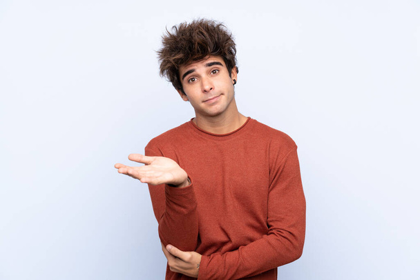 Young caucasian man over isolated blue background unhappy for not understand something - Photo, Image