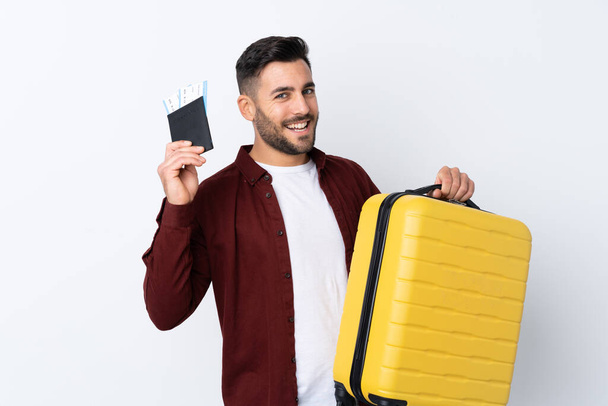 Joven hombre guapo sobre fondo blanco aislado en vacaciones con maleta y pasaporte
 - Foto, Imagen