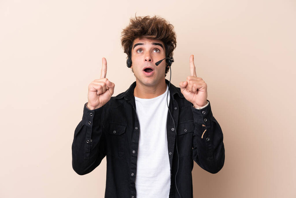 Hombre telemarketer trabajando con un auricular sobre fondo aislado apuntando con el dedo índice una gran idea
 - Foto, imagen