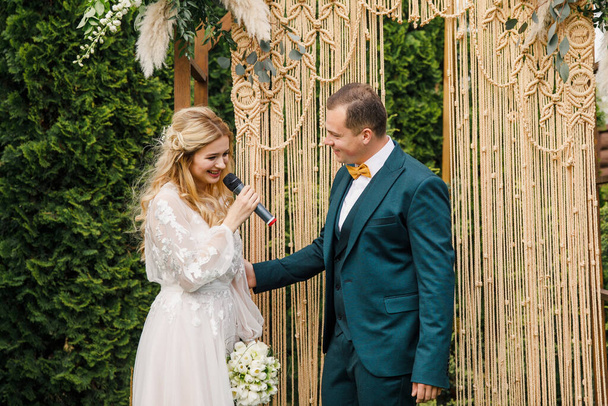beautiful boho style wedding ceremony. The bride in a beautiful dress and the groom in a classic suit - Фото, зображення