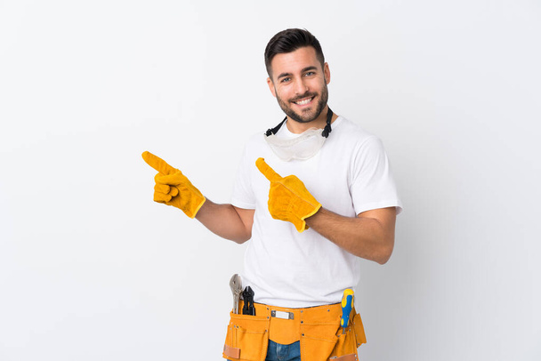 Craftsmen or electrician man over isolated white background pointing finger to the side - Foto, imagen