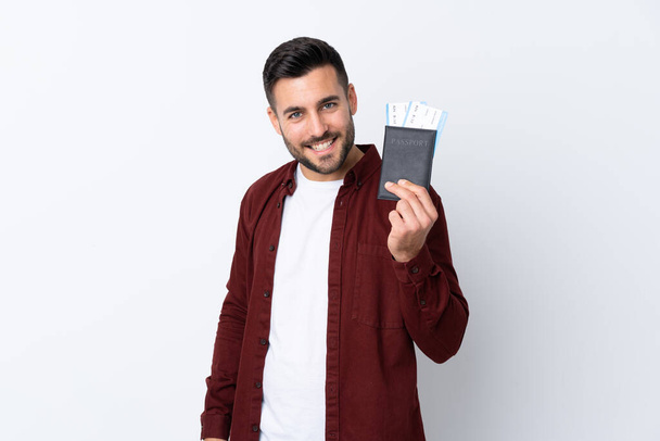 Young handsome man over isolated white background happy in vacation with passport and plane tickets - Fotó, kép