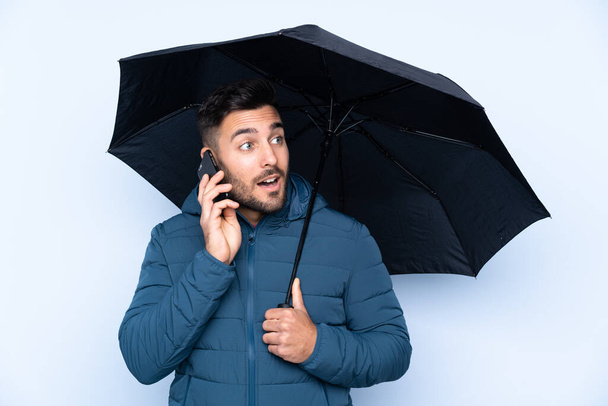 Άντρας που κρατάει ομπρέλα σε απομονωμένο φόντο - Φωτογραφία, εικόνα