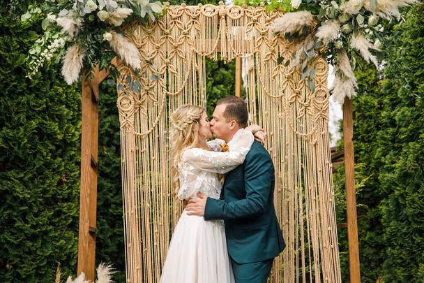 beautiful boho style wedding ceremony. The bride in a beautiful dress and the groom in a classic suit - Foto, afbeelding