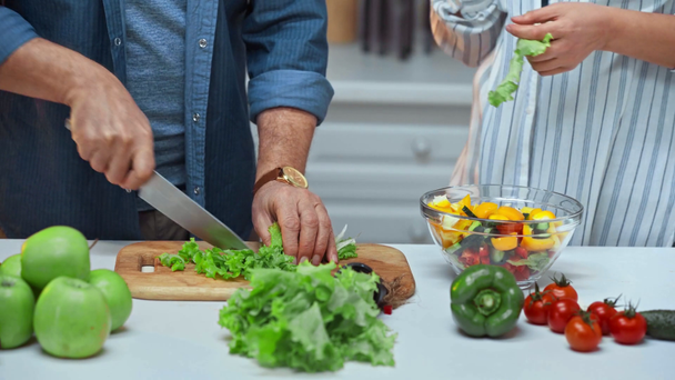 ostříhaný pohled na starší pár, jak dělá salát v kuchyni  - Záběry, video