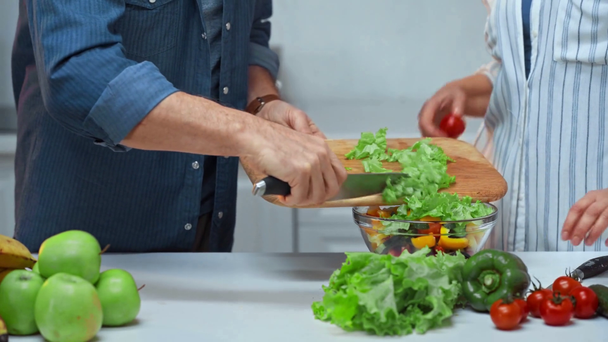 ostříhaný pohled na starší pár připravující salát v kuchyni  - Záběry, video