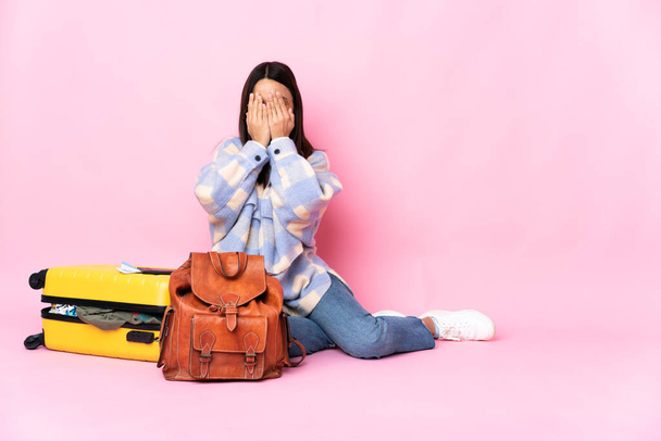 Traveler woman with a suitcase sitting on the floor covering eyes by hands - Foto, Bild