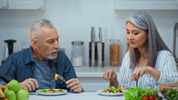 上級異人種間のカップルはキッチンでサラダを食べる  - 映像、動画