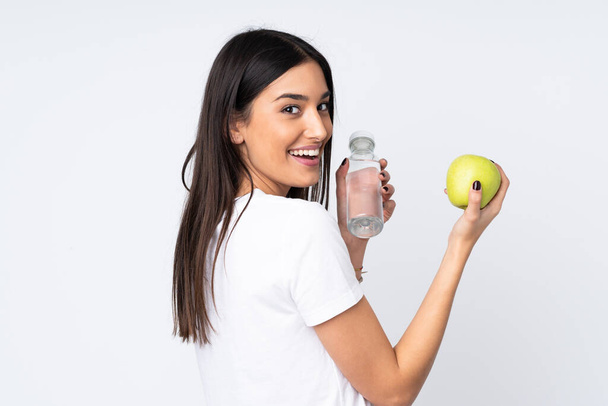 Giovane donna caucasica isolata su sfondo bianco con una mela e con una bottiglia d'acqua - Foto, immagini