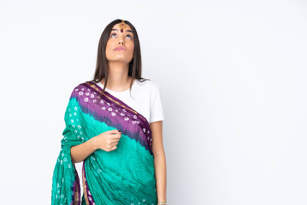 Genç Hintli kadın beyaz arka planda izole edilmiş ve yukarı bakıyor. - Fotoğraf, Görsel