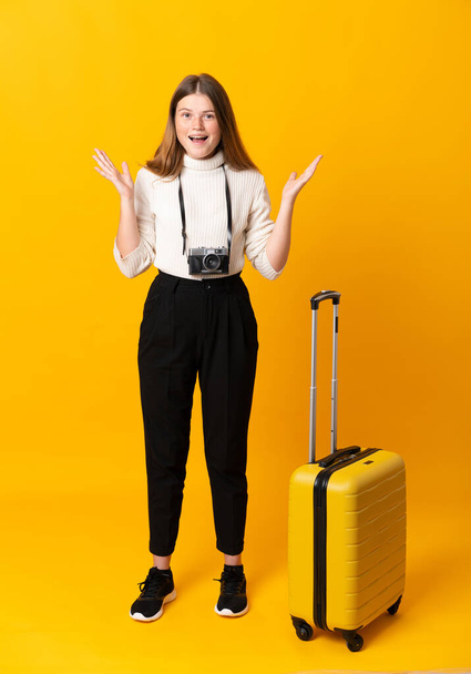 Koko kehon matkustava teini tyttö matkalaukku yli eristetty keltainen tausta yllätys kasvojen ilme
 - Valokuva, kuva