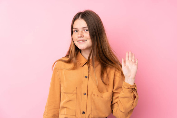 Ukrainian teenager girl over isolated pink background saluting with hand with happy expression - Photo, Image
