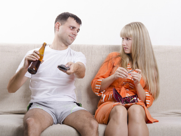La pareja en el sofá. Se ve bebiendo cerveza, ella lo mira con reproche
 - Foto, Imagen