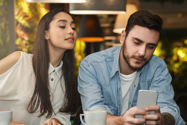 Girlfriend Reading Boyfriends Messages Behind His Back In Cafe - Foto, imagen