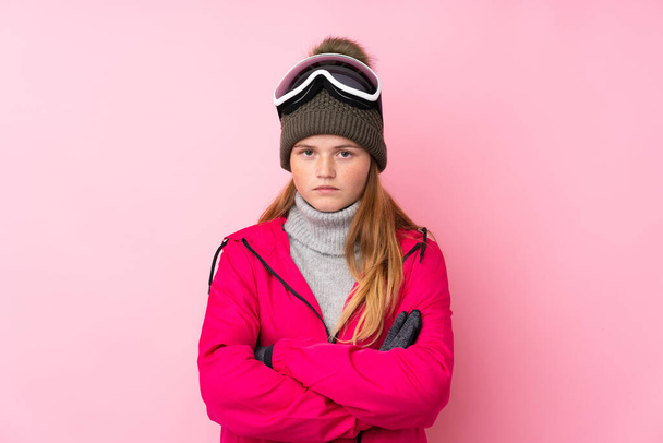 Jeune skieuse ukrainienne avec des lunettes de snowboard sur fond rose isolé gardant les bras croisés
 - Photo, image