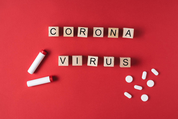 Textová fráze Koronavirus na dřevěných kostkách na červeném pozadí s tabletami. Novel coronavirus 2019-nCoV, MERS-Cov respirační syndrom středního východu. - Fotografie, Obrázek