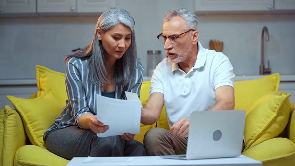 scontento anziani coppia interrazziale guardando le bollette vicino laptop
  - Filmati, video