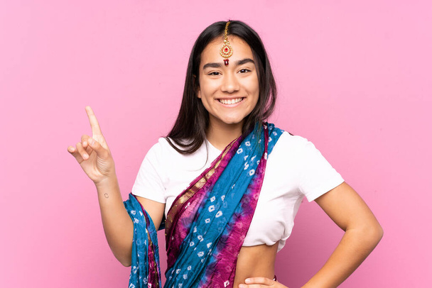 Fiatal indiai nő szári felett elszigetelt háttér mutatja és emeli az ujját jele a legjobb - Fotó, kép