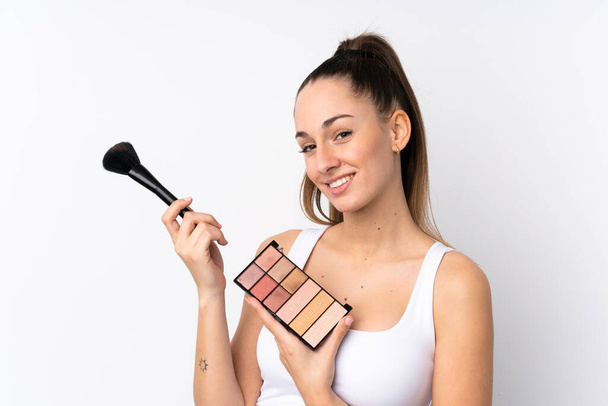jonge brunette vrouw over geïsoleerde witte achtergrond met make-up palet - Foto, afbeelding
