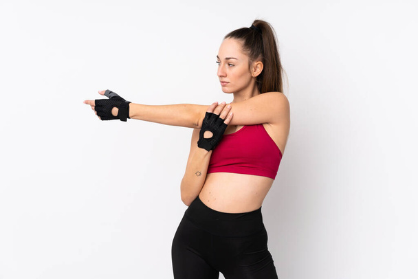 Jonge sport brunette vrouw over geïsoleerde witte achtergrond stretching arm - Foto, afbeelding