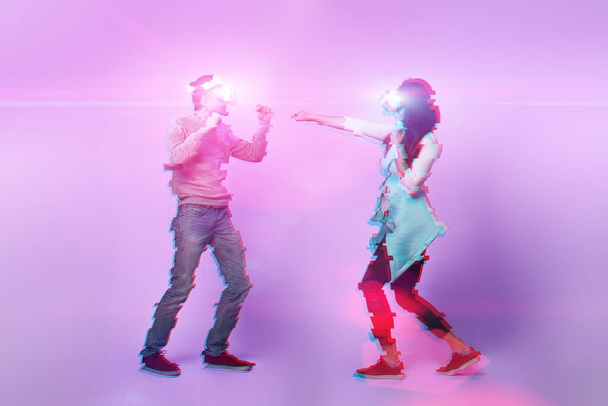 Couple with virtual reality headset are playing game and fighting. Image with glitch effect. - Foto, Imagen
