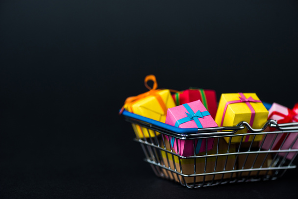 selective focus of gift boxes in shopping basket isolated on black  - Photo, Image